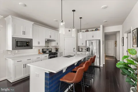 a kitchen with stainless steel appliances a stove a refrigerator a white table and chairs