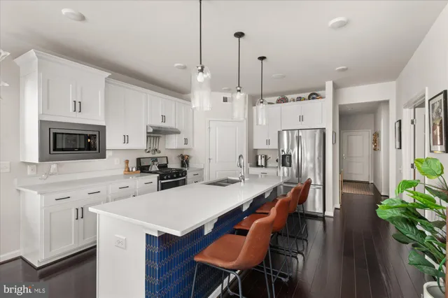 a kitchen with stainless steel appliances a stove a refrigerator a white table and chairs