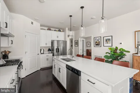 a kitchen that has a lot of white cabinets and stainless steel appliances