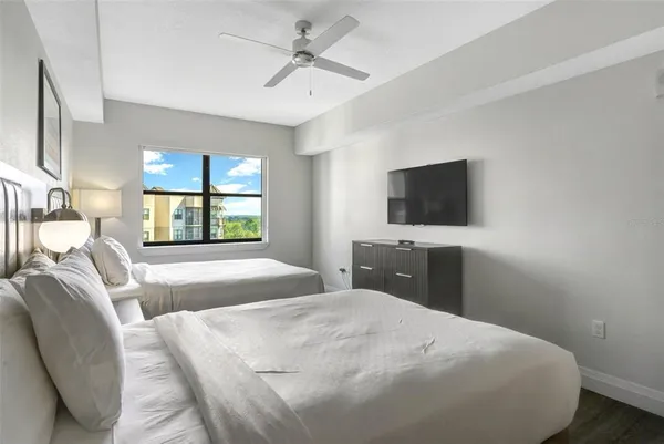 a bedroom with a bed a tv and wooden floor