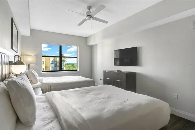 a bedroom with a bed a tv and wooden floor