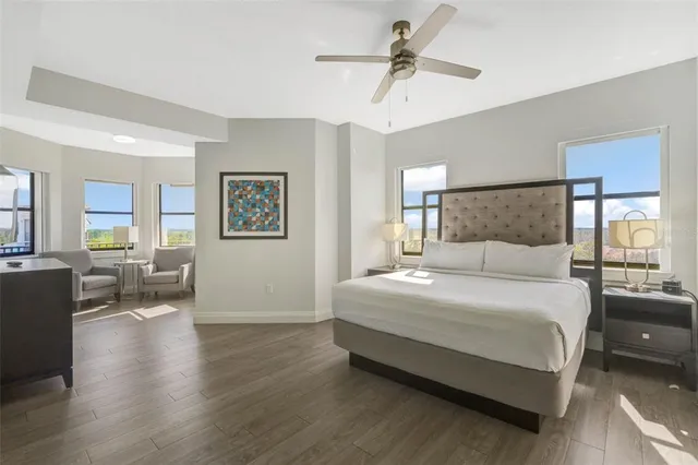 a bedroom with a large bed a chandelier and windows