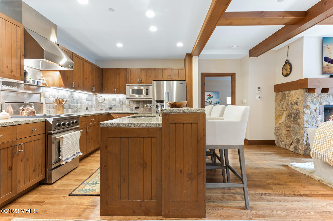 180 Daybreak Ridge Road, Unit 309 Avon, CO 81620 - Photo 13 of 27 a kitchen with stainless steel appliances kitchen island granite countertop a stove a sink a dining table and chairs with wooden floor