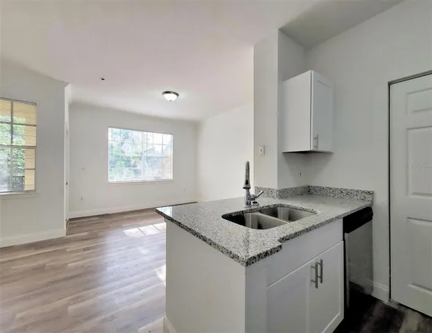 a kitchen with granite countertop kitchen island a sink a stove and wooden floor