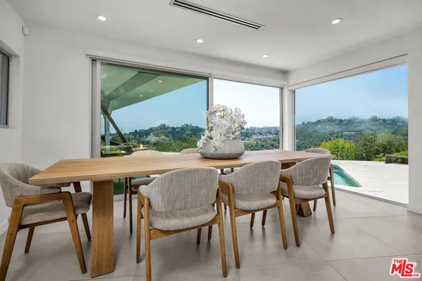a dining room with furniture a rug and a floor to ceiling window