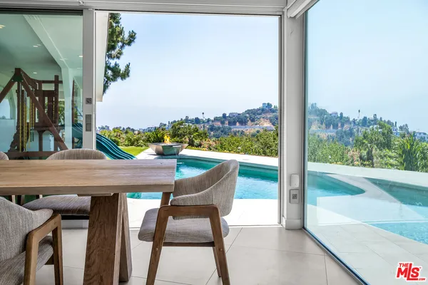 a living room with furniture a rug kitchen view and a large window
