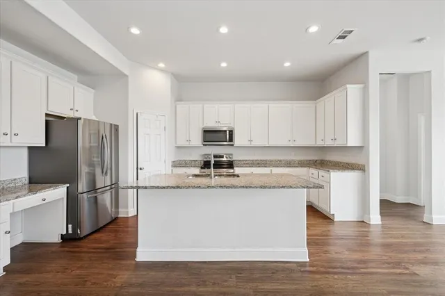 a kitchen with granite countertop cabinets stainless steel appliances and a wooden floor