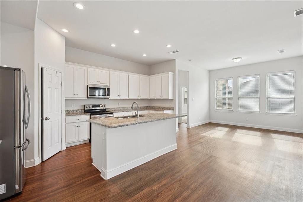 313 Marble Creek Drive Fort Worth, TX 76131 - Photo 9 of 27 a kitchen with stainless steel appliances granite countertop a refrigerator a sink dishwasher a stove and white cabinets with wooden floor
