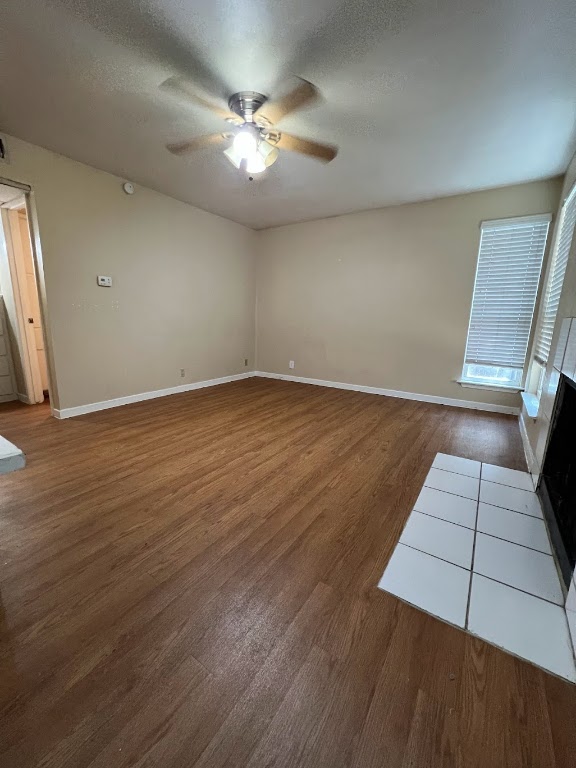 1000 West 26th Street, Unit 101 Austin, TX 78705 - Photo 3 of 10 Empty room featuring baseboards, a ceiling fan, wood finished floors, and a textured ceiling