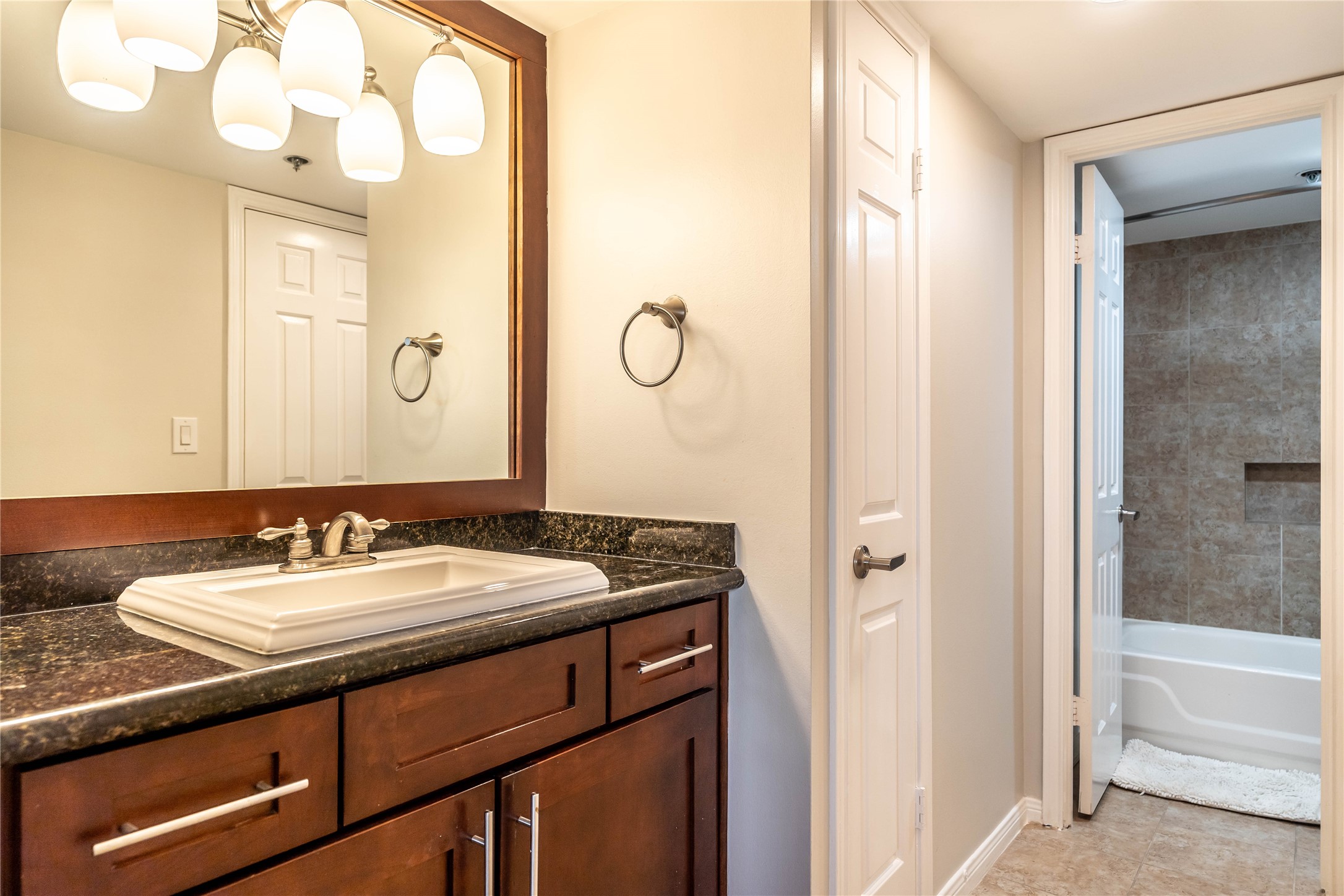 3525 Sage Road, Unit 1315 Houston, TX 77056 - Photo 10 of 20 a bathroom with a granite countertop sink a mirror and a bathtub