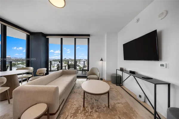 a living room with furniture a flat screen tv and a floor to ceiling window