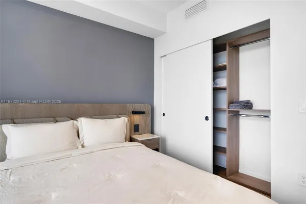 a bedroom with a large bed and a flat tv screen on dresser