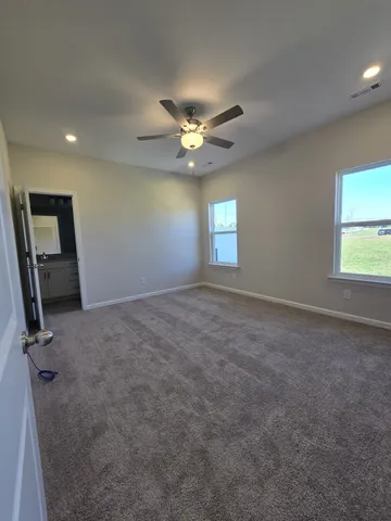 an empty room with windows and fan