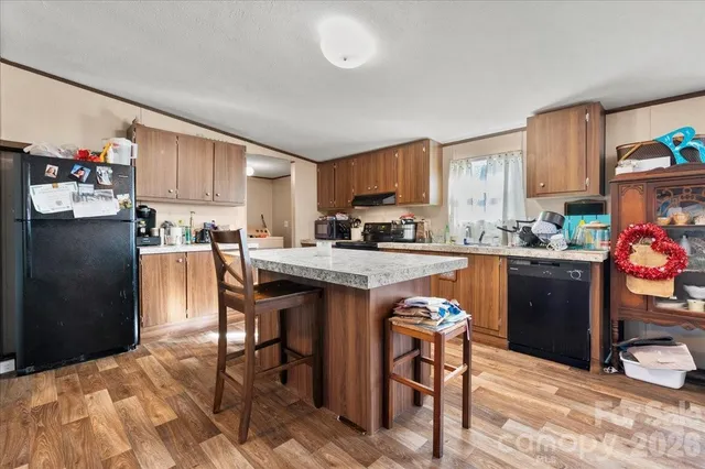 a kitchen with granite countertop wooden cabinets a refrigerator a stove a sink and a dining table with wooden floor