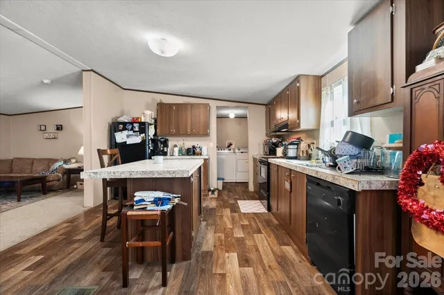 a kitchen with stainless steel appliances a sink a stove a refrigerator cabinets and living room view