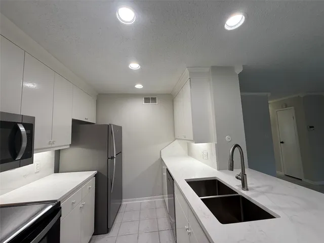 a kitchen with stainless steel appliances a sink a stove a microwave a counter top space and cabinets