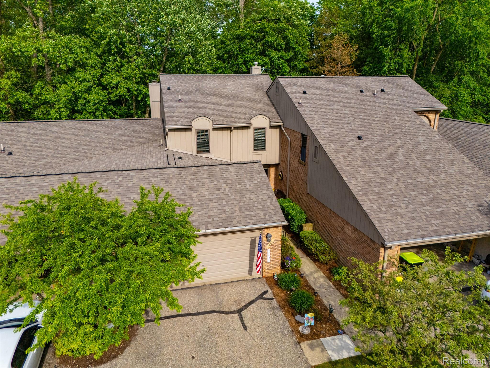1687 Lodge Pole Lane Rochester, MI 48309 - Photo 33 of 53 Multi-level roofline with asphalt shingles, featuring dormer windows, brick and siding exterior, and an attached garage