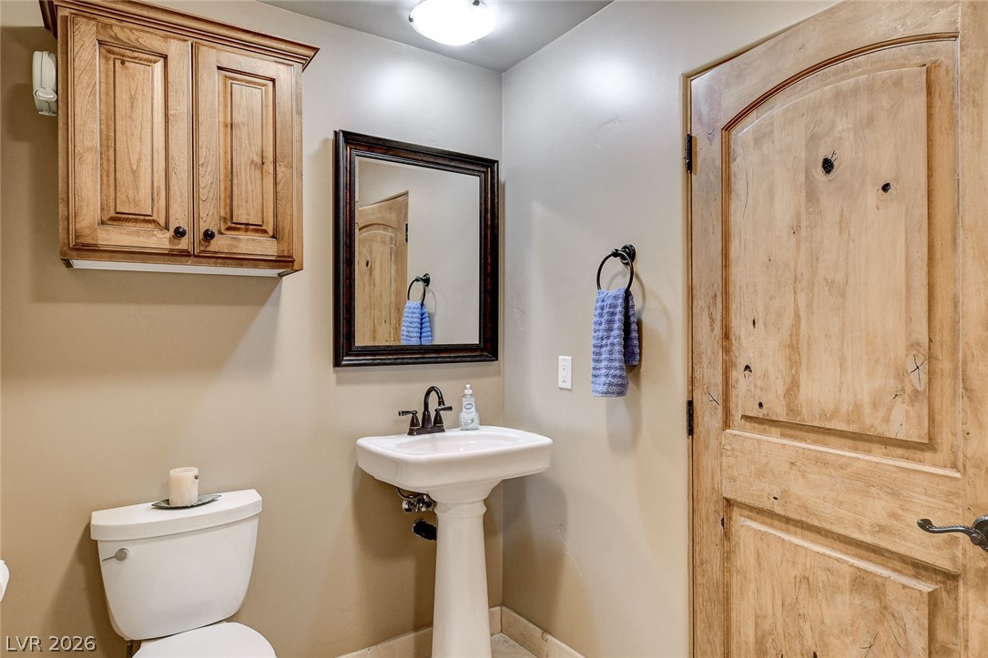 1950 Bowman Road Logandale, NV 89021 - Photo 45 of 81 A compact bathroom offers a pedestal sink and charming wooden cabinetry.