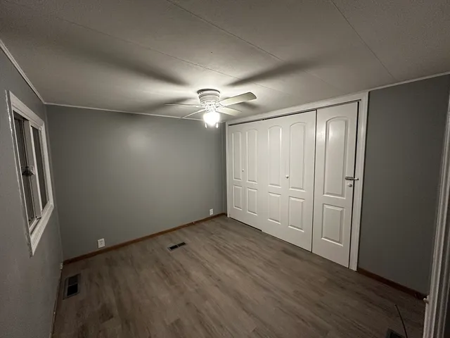 an empty room with wooden floor and a ceiling fan