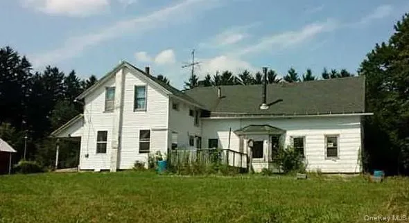 a view of a white house next to a yard with big trees