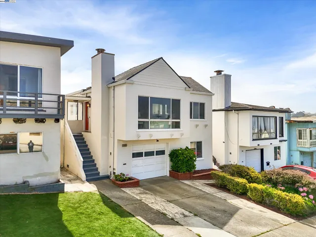 a front view of a house with a yard and potted plants