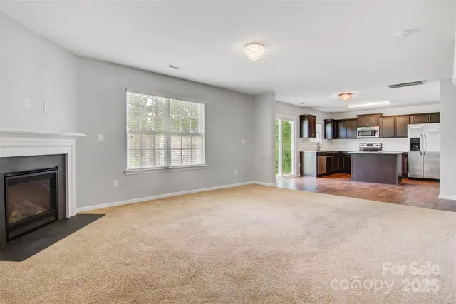 a view of empty room with kitchen and fireplace