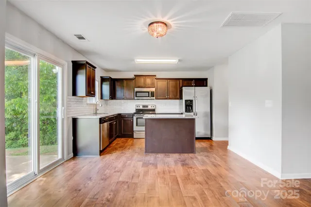 a large kitchen with stainless steel appliances granite countertop a stove sink and cabinets