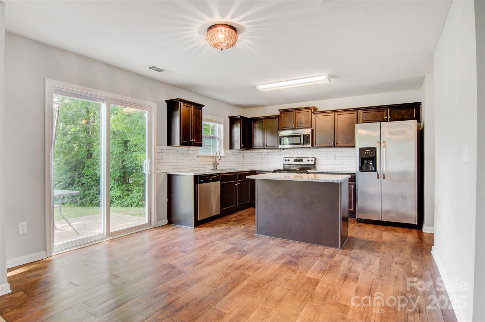 5311 Oakdale Ridge Road Charlotte, NC 28216 - Photo 13 of 35 a large kitchen with stainless steel appliances granite countertop a stove top oven a sink dishwasher a refrigerator white cabinets and wooden floor