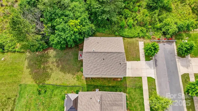 an aerial view of a house with a yard and trees all around