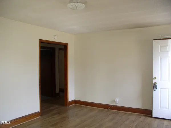 a view of an empty room with wooden floor and closet