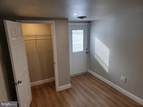 an empty room with wooden floor and mirror