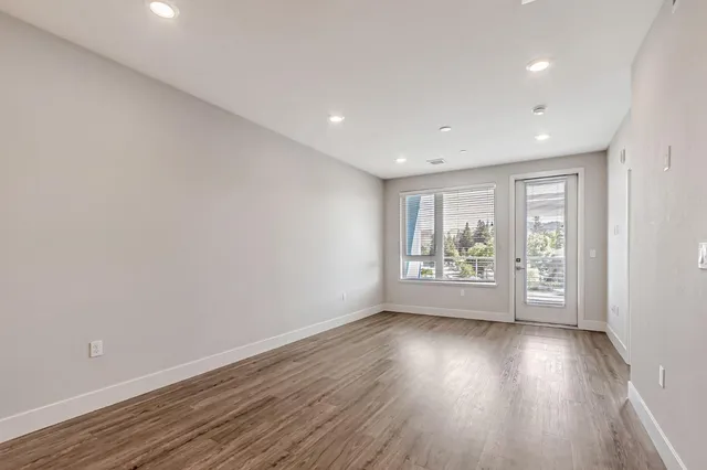 a view of an empty room with wooden floor and a window