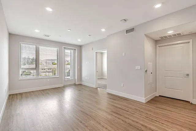 a view of an empty room with wooden floor and a window