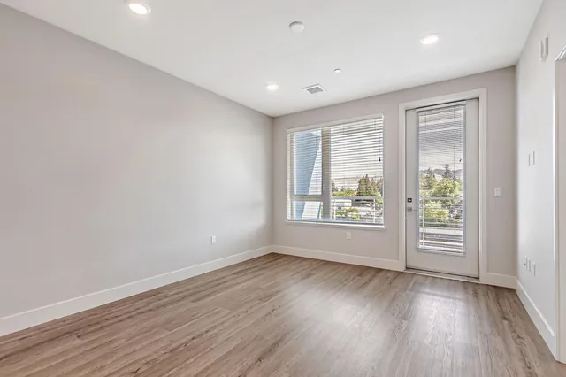 an empty room with wooden floor and windows