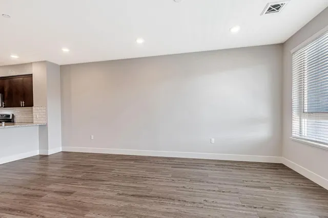 a view of an empty room with wooden floor and a window