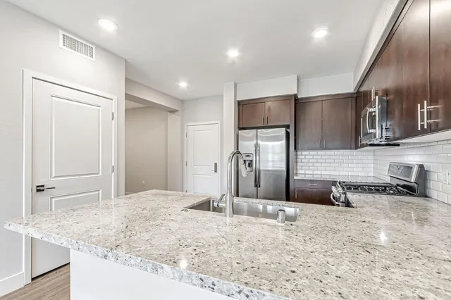 a kitchen with stainless steel appliances granite countertop a sink refrigerator and microwave