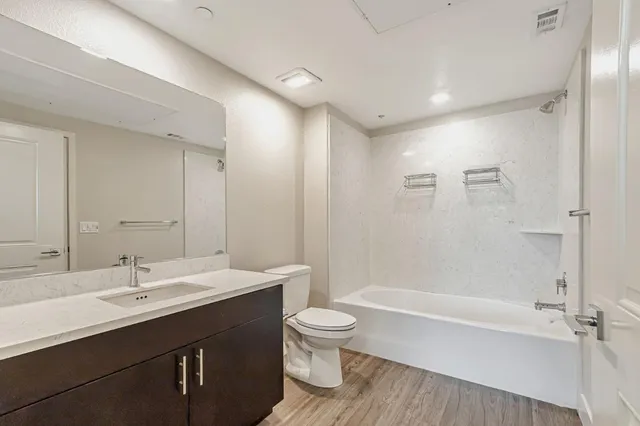 a bathroom with a bathtub shower sink mirror and toilet
