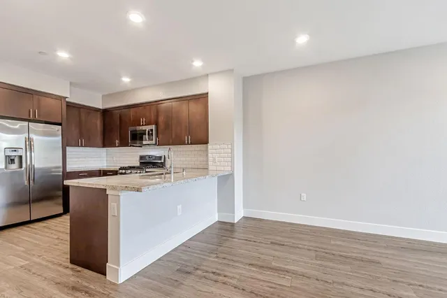 a kitchen with stainless steel appliances granite countertop a refrigerator a stove and a microwave with wooden floor