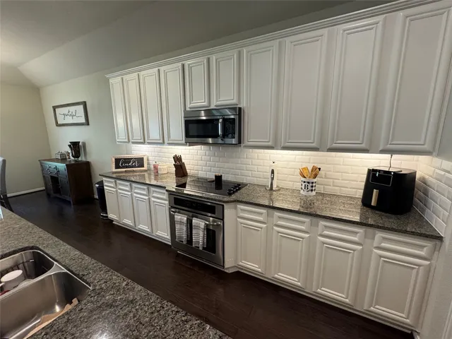 a kitchen with stainless steel appliances granite countertop a sink a stove and a microwave