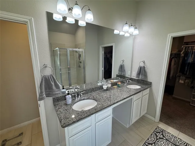 a bathroom with a granite countertop double vanity and a mirror