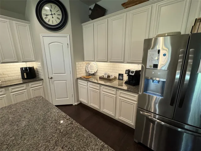 a kitchen with stainless steel appliances granite countertop a refrigerator a stove and a refrigerator with white cabinets