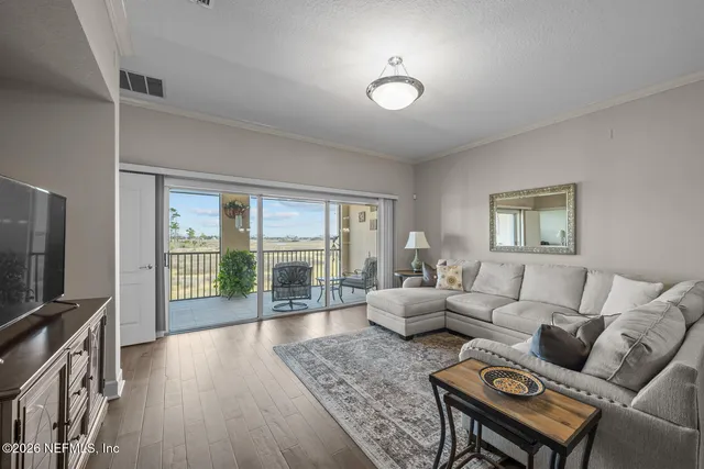 a living room with furniture a flat screen tv and a floor to ceiling window