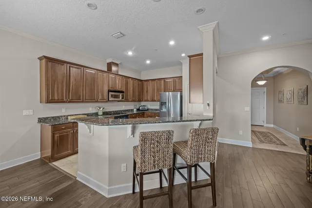 a kitchen with stainless steel appliances granite countertop a kitchen island hardwood floor sink and stove