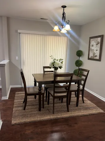 a dining room with wooden floor a chandelier a wooden table and chairs