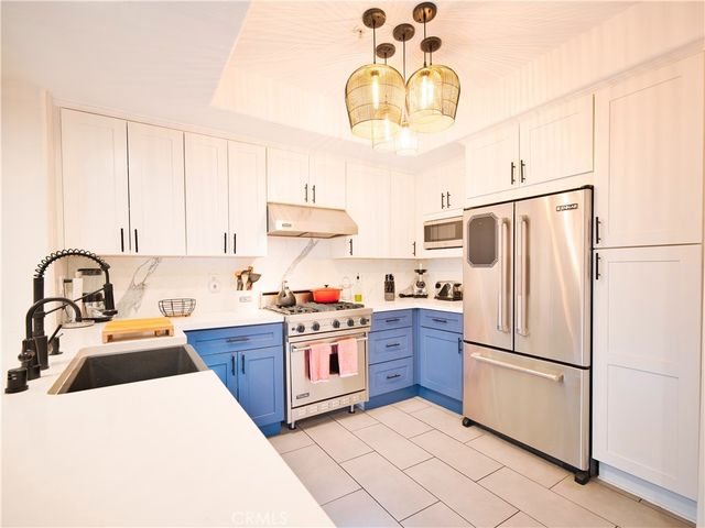 a kitchen with stainless steel appliances granite countertop a refrigerator a stove a sink dishwasher and white cabinets with wooden floor