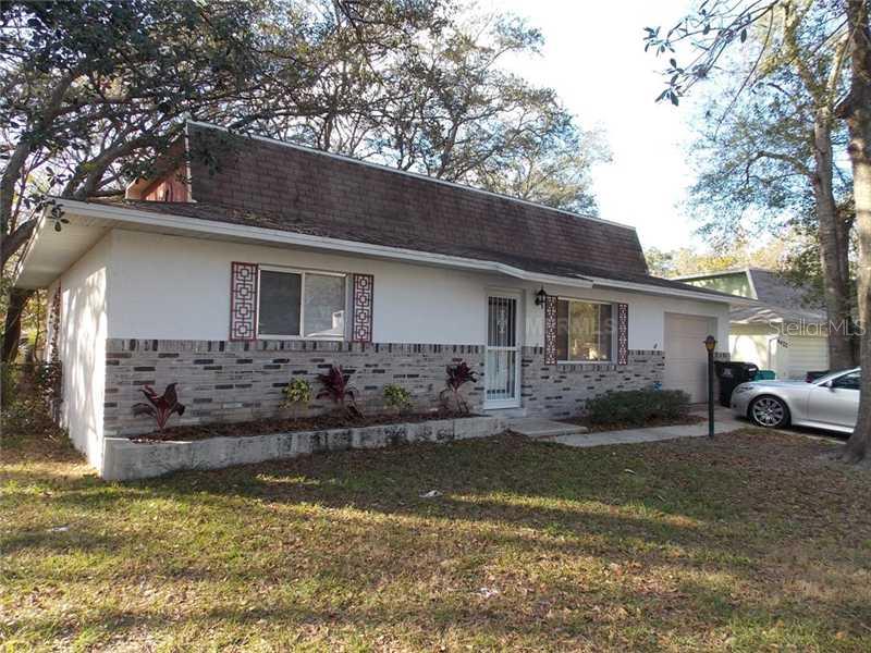 4414 Sebastian Way Orlando, FL 32808 - Photo 1 of 1 a house that has a large tree in front of it