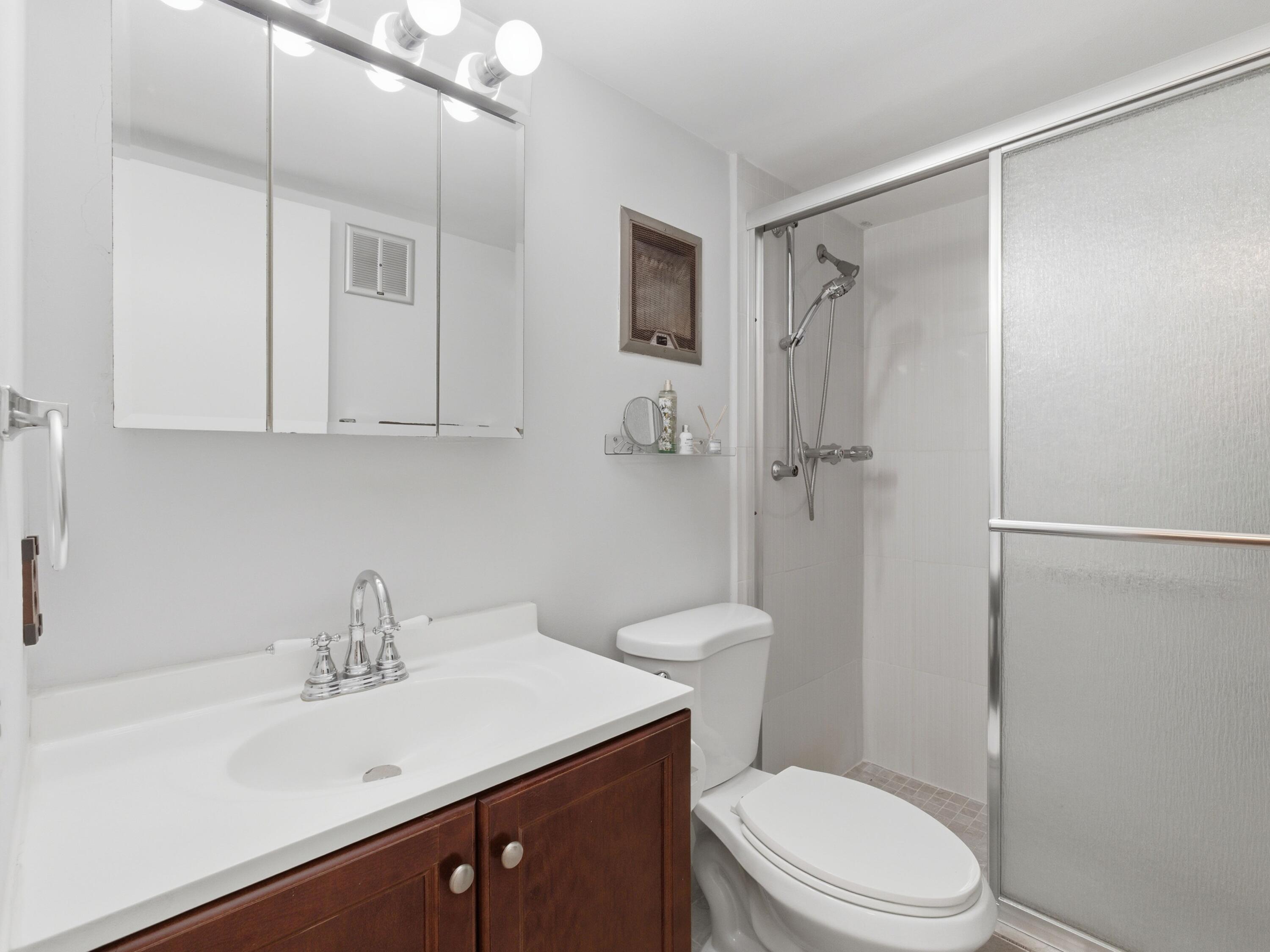 400 Northeast 20th Street, Unit A216 Boca Raton, FL 33431 - Photo 22 of 32 a bathroom with a sink a toilet a shower and a mirror