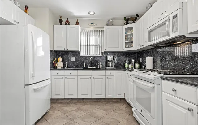 a kitchen with white cabinets and white appliances