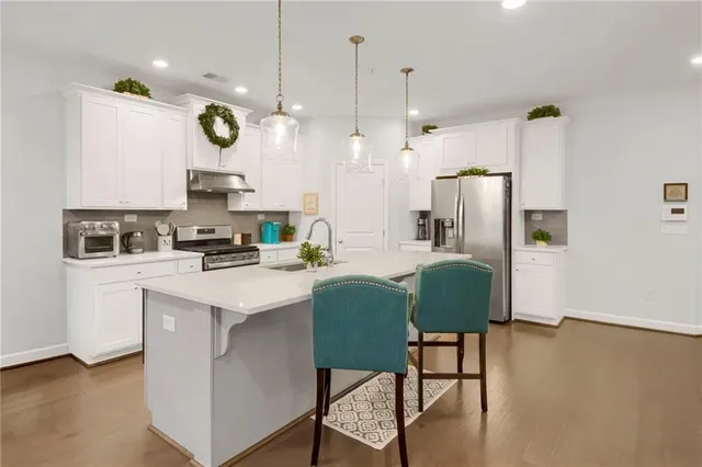 a kitchen with a refrigerator a microwave a stove and white cabinets with wooden floor