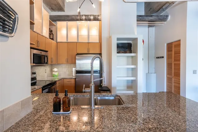 a kitchen with stainless steel appliances granite countertop a sink and a refrigerator